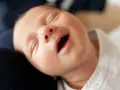 Uśmiechnięta buzia niemowlaka, kiedy dziecko zaczyna się śmiać. Radość maluszka.