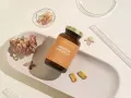Suplement Omega-3 z DHA dla kobiet w ciąży, wspierający rozwój mózgu dziecka. Na zdjęciu buteleczka i kapsułki na tle suszonych kwiatów.