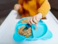 Małe rączki sięgają po łyżeczkę, by spróbować pysznej owsianki dla niemowlaka.