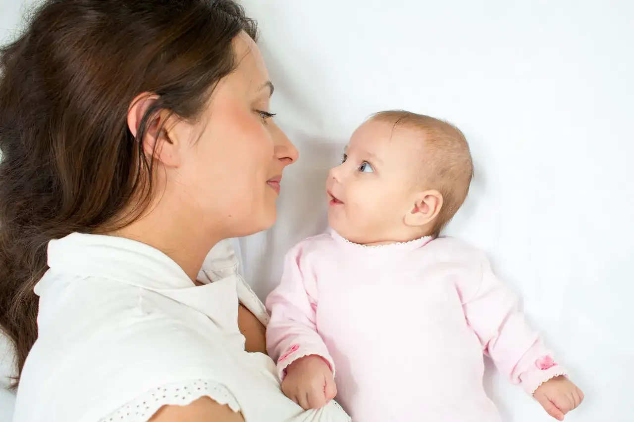 Mama patrzy na swoje dziecko, które właśnie zaczyna się uśmiechać. Cudowny moment.